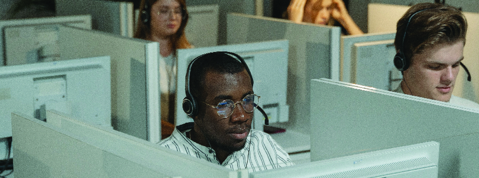people sitting at a desk in a call centre answering callings